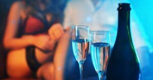 Champagne glasses in front view, female strip girl is sitting behind the glasses